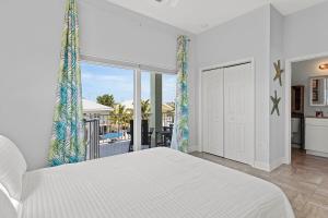 a white bedroom with a large bed and a balcony at Tipsy Turtle - Waterfront Pool Home, Direct Atlantic Access! in Marathon