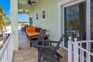 a porch with chairs and a table on a balcony at Tipsy Turtle - Waterfront Pool Home, Direct Atlantic Access! in Marathon