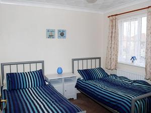 a bedroom with two beds and a desk and a window at Sea Breeze Bungalow in Sutton on Sea