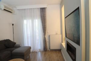 a living room with a couch and a large window at Meraki Living in Néa Michanióna