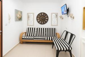 eine Couch und ein Sessel in einem Raum mit einer Uhr in der Unterkunft Apartment in Roatan ! in Coxen Hole