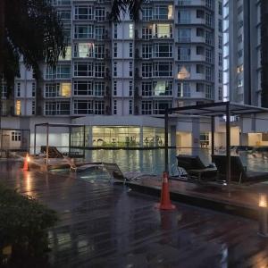 a building with chairs and an umbrella in the rain at CharmsStays Central Residence Sg Besi in Kuala Lumpur