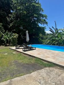 an umbrella and chairs next to a swimming pool at Appartement moderne à Petit-Bourg, 70 m², piscine privée in Petit-Bourg