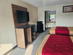 a hotel room with a bed and a flat screen tv at Studios 4 Less Chesapeake in Chesapeake
