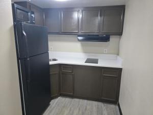 a kitchen with brown cabinets and a black refrigerator at Studios 4 Less Chesapeake in Chesapeake