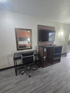 een kamer met een bureau, een tv en een stoel bij Studios 4 Less Chesapeake in Chesapeake