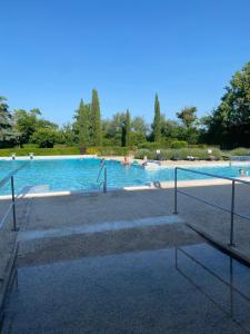 a large swimming pool with people in the water at Les Papillons in Verteillac
