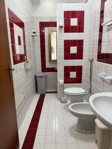 a bathroom with two toilets and red and white tiles at Il cortiletto in Menfi +13 photos