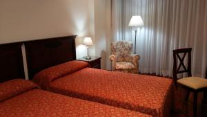 a hotel room with two beds and a chair at Apartamentos Maritimo Suites-Solo Adultos in O Grove +81 photos