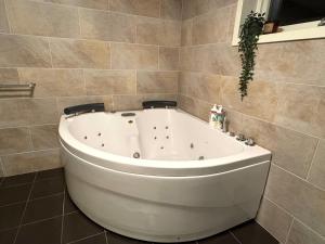 MalvikにあるApartment with garden and large bathroomのタイル張りの壁のバスルーム(白いバスタブ付) +16枚の写真