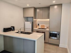 a kitchen with a sink and a refrigerator at Cozy APT close to Accor Stadium in Sydney