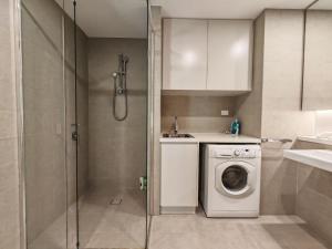 a bathroom with a washing machine and a shower at Cozy APT close to Accor Stadium in Sydney +3 photos