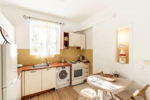 cocina con armarios blancos, mesa y fregadero en Cozy, Romantic Studio next to The Mall, en Atenas