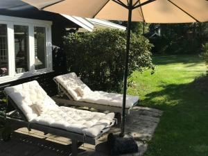 two couches sitting on a patio under an umbrella at Summerhouse By Tisvilde Hegn Forest in Tisvildeleje