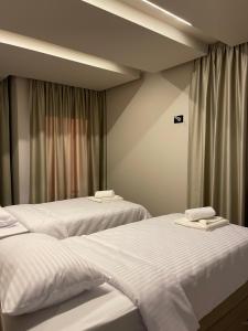 two beds in a hotel room with white sheets at Apartmani Mila Mi in Kotor-Varoš