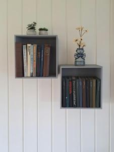 two shelves with books on them on a wall at Cottage Charm Near Lønstrup Lighthouse in Lønstrup +12 photos
