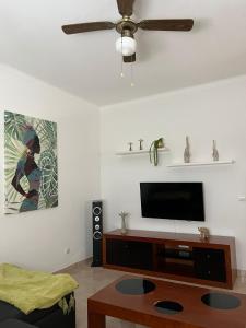 sala de estar con TV de pantalla plana y ventilador de techo en Casa da Margarida, en Castro Marim