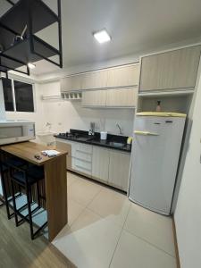 a kitchen with a white refrigerator and a table at Apto novo completo - localização privilegiada in Joinville +9 photos