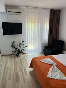 a hotel room with a bed and a chair and a television at Studio 1 & Studio 2 Aqua in Eforie Nord