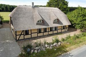 an old house with a thatched roof on a street at Nostalgic Charm In A Yellow Timber House in Sakskøbing