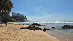 a beach with some rocks and the ocean at Unawatuna Nature Villa in Unawatuna
