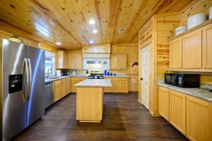 Una cocina con gabinetes de madera y un refrigerador de acero inoxidable. en Outlaw Rose Cabin - Family Fun with Hot Tub, en Broken Bow 35 fotos más