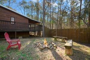 Una fogata y una silla roja en un patio. en Outlaw Rose Cabin - Family Fun with Hot Tub, en Broken Bow