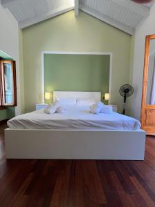 a large white bed in a room with a wooden floor at Campidoglio vacation home in Lenno