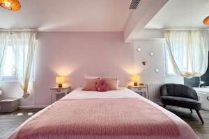 a bedroom with a large bed with a pink blanket at Studio rose & spa Pause bien-être in Quéven