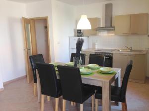 a dining room table with black chairs and a kitchen at Apartmani Kvesic - Azzurro in Šilo