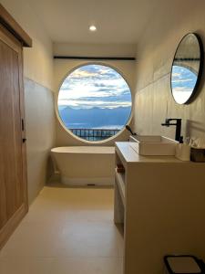 a bathroom with a tub and a large window at D Alam Batur in Kubupenlokan