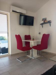 a room with a table and four red chairs at Apartmani Versizo Rogoznica in Sevid