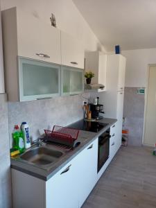 a kitchen with white cabinets and a sink at Apartmani Versizo Rogoznica in Sevid