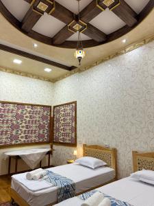 a bedroom with two beds and a chandelier at Firdavsiy Guesthouse - Уютный Апарт-отель у озера in Bukhara