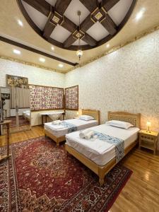 a bedroom with two beds and a rug at Firdavsiy Guesthouse - Уютный Апарт-отель у озера in Bukhara