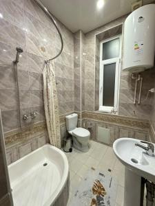 a bathroom with a tub and a toilet and a sink at Firdavsiy Guesthouse - Уютный Апарт-отель у озера in Bukhara