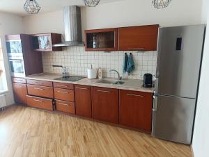 a kitchen with wooden cabinets and a stainless steel refrigerator at Max apartments 2 in Klaipėda