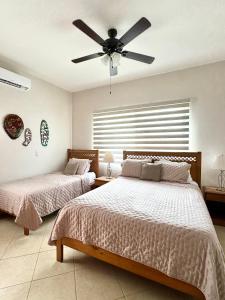 two beds in a bedroom with a ceiling fan at Casa Suerte in Coco +29 photos