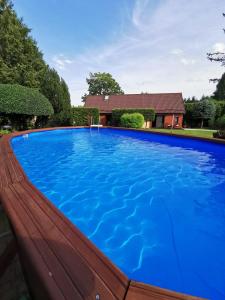 a large blue swimming pool in front of a house at Ostoja Relaksu Cieciorka in Kaliska