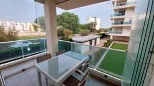 a balcony with a glass table and chairs at Este in La Playa de la Torre de Piles