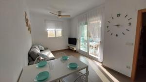 a living room with a table and a clock on the wall at Este in La Playa de la Torre de Piles