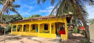 a yellow house with a hammock in front of it at Canto da Zaya in Soure