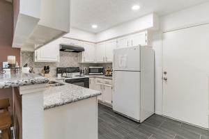 Una cocina con gabinetes blancos y un refrigerador blanco. en SW Houston Eclectic Living, en Houston