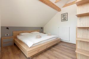 Schlafzimmer mit einem Bett mit weißer Bettwäsche und Holzböden in der Unterkunft Brlog 2 in Zgornje Gorje