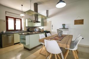 a kitchen with a wooden table and white chairs at Villa Mattei in Oristano