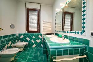 a green tiled bathroom with two sinks and two toilets at Villa Mattei in Oristano +36 photos