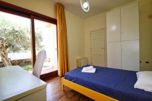 a bedroom with a blue bed and a large window at Villa Mattei in Oristano