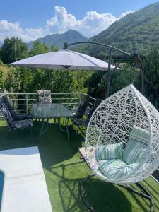 a white swing with an umbrella and a table and chairs at Vila sa bazenom Lily in Konjic