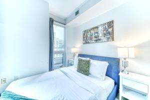 a white bedroom with a bed and a window at RivetStays - The Jarvis in Toronto
