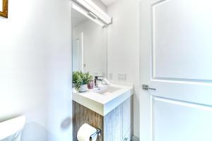 a white bathroom with a sink and a mirror at RivetStays - The Jarvis in Toronto